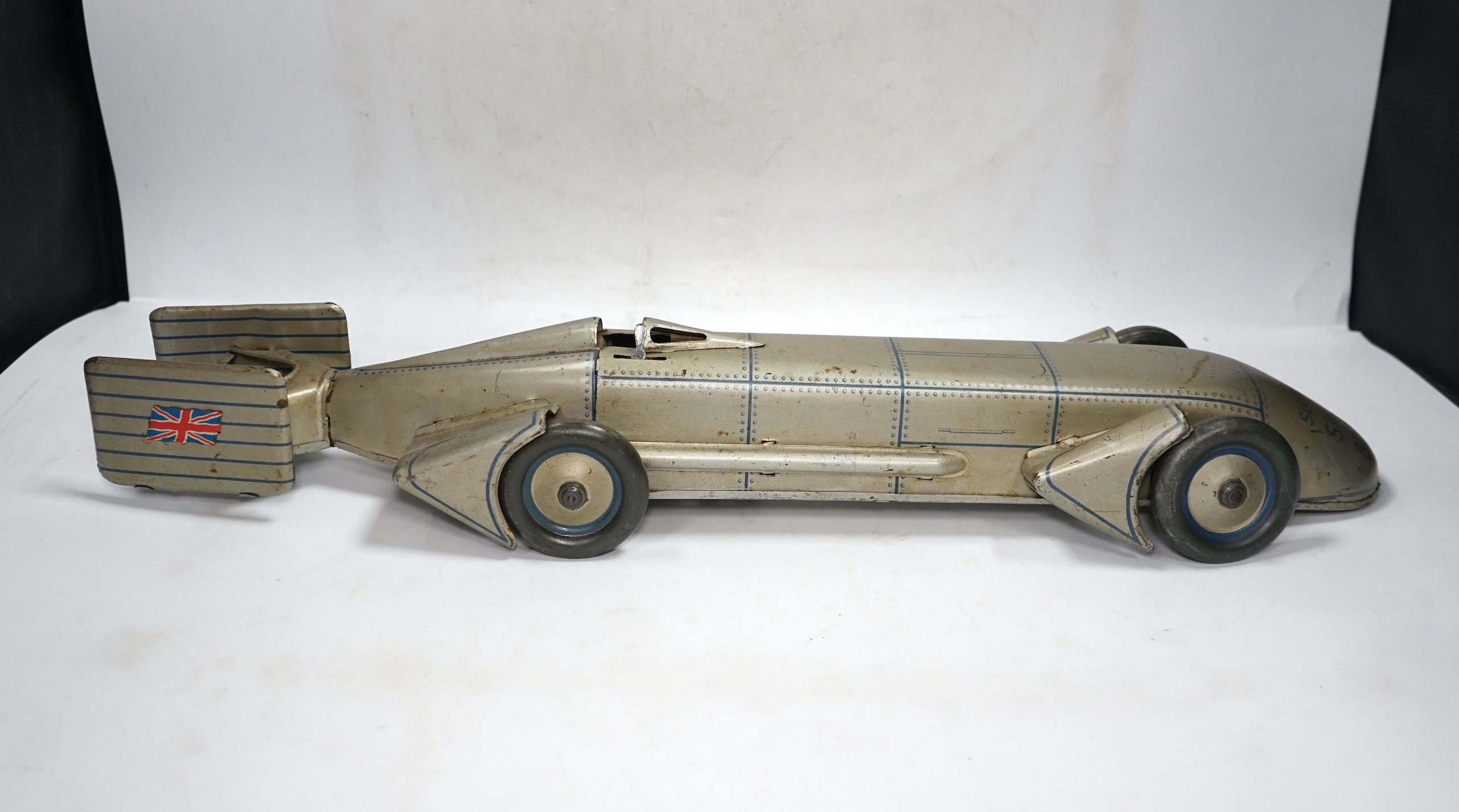 A 1930s Gunthermann (Germany) clockwork tinplate Sunbeam Silver Bullet world record car, with blue printed panel and rivet detail, driver, and Union flags to tail fins, stamped with ‘Foreign’ to underside, 56cm long. Con